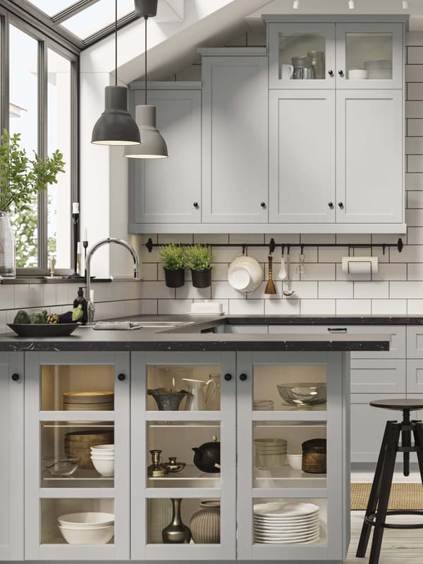 A LERHYTTAN light gray kitchen surrounded by large windows with sunlight and plants.