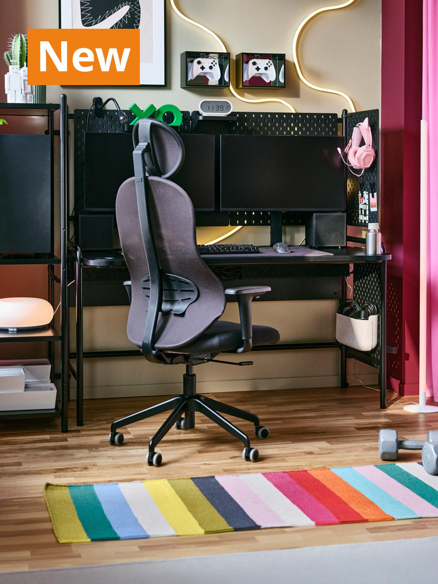A lifestlye image of a gaming room with UTKLASSNING gaming chair in anthracite black and a gaming desk. Overlaying the image, orange tag that reads 'New' on the top left corner.