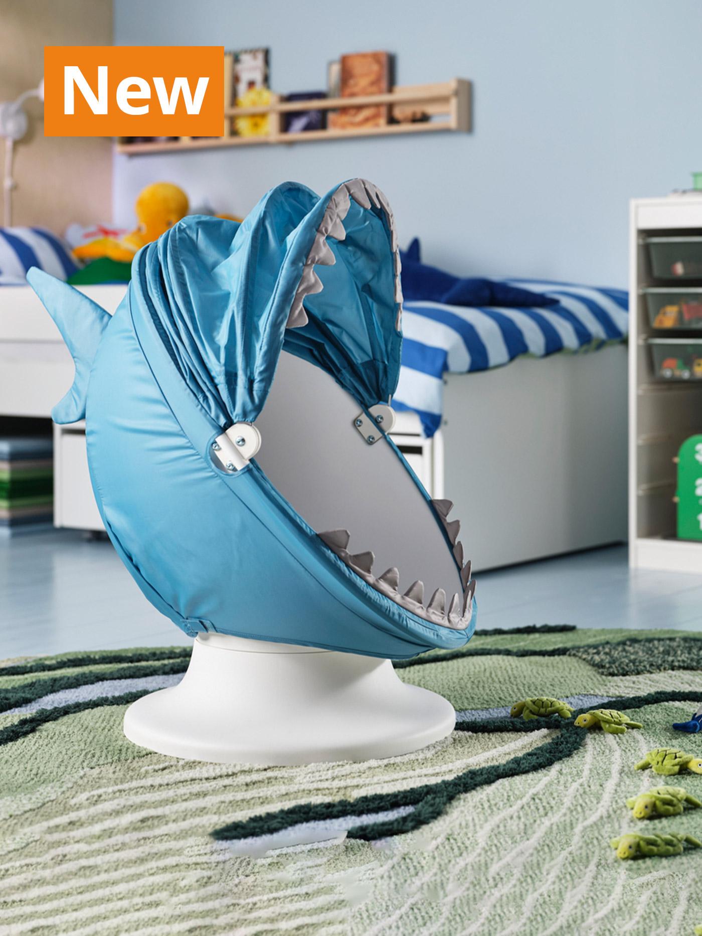 A lifestyle image of blue shark IKEA PS LÖMSK children's accessories placed on a white IKEA PS LÖMSK
Children's swivel armchair in a children's bedroom setting. Overlaying the image, orange tag that reads 'New' on the top left corner.