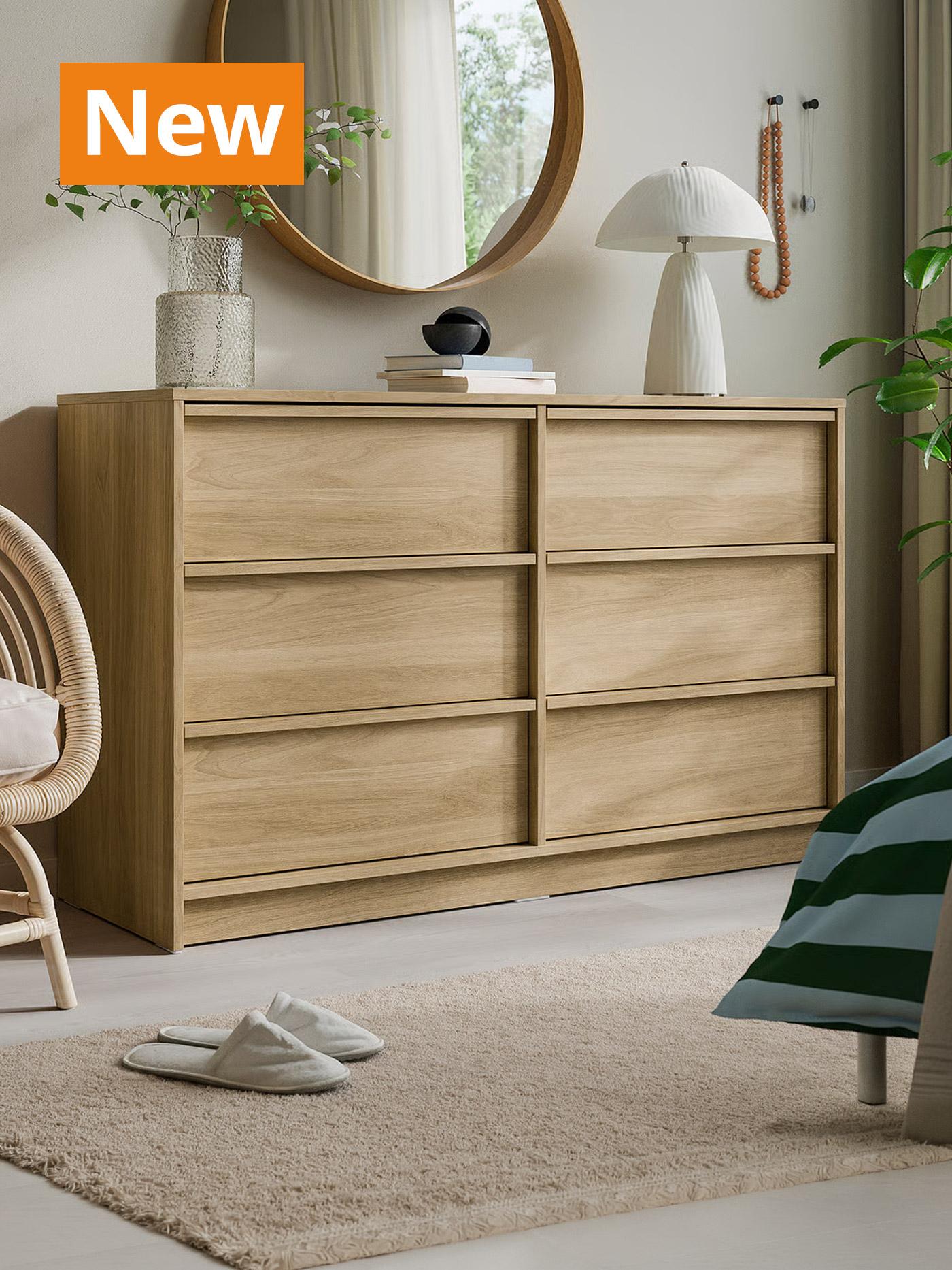 A lifestyle photo featuring the oak effect ANKARUDDEN chest of 6 drawers in a bedroom setting. Overlaying the image, orange tag that reads 'New' on the top left corner.