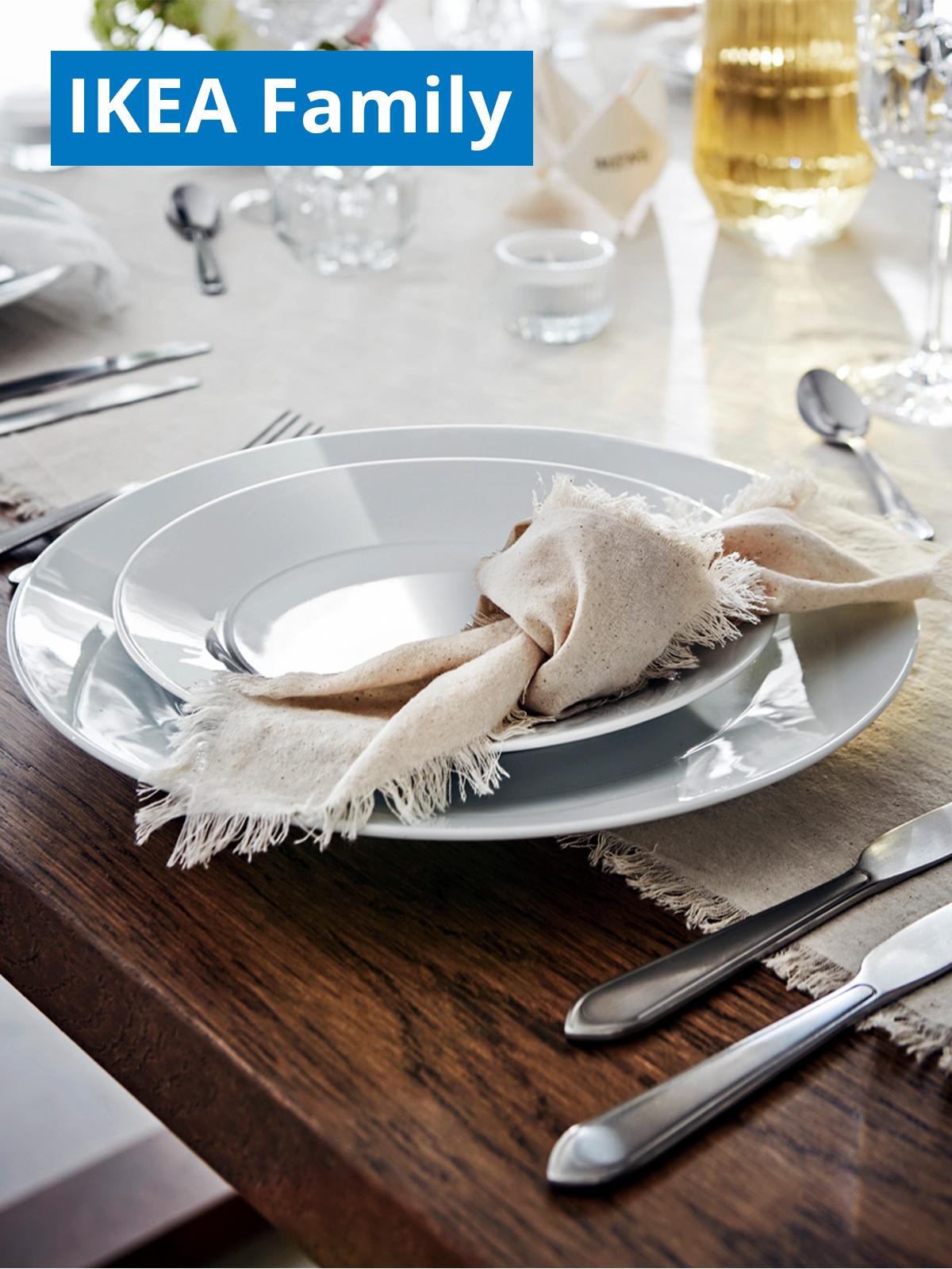 A lifestyle shot of dining table setting featuring IKEA 365+ 18-piece service plates. On the top left corner, a blue tag with white text that reads "IKEA Family price".