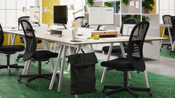 A light, airy office with several black FLINTAN office chairs around a cluster of TROTTEN desks, forming a shared workspace.
