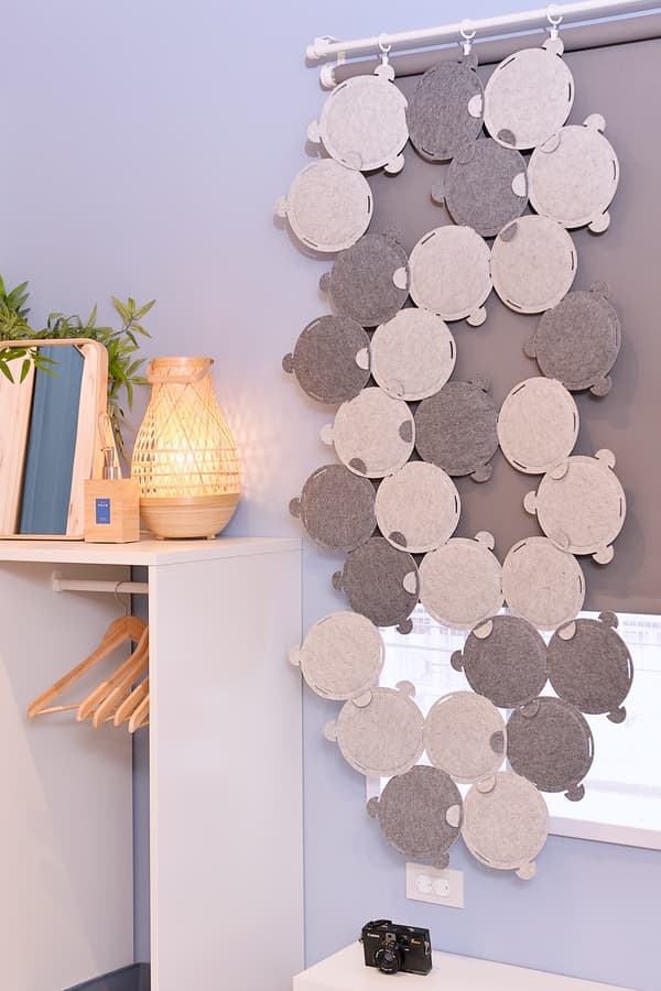 A light blue wall featuring sound absorbing panels and a cabinet with a lamp placed on top.