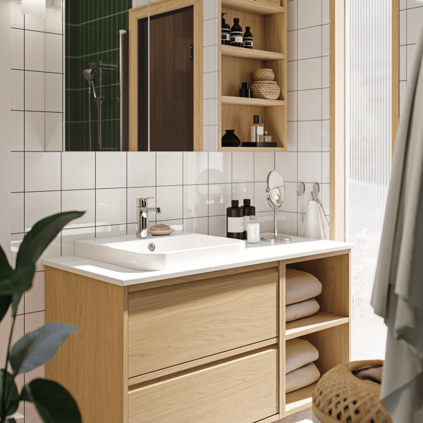 A light brown oak veneer bathroom furniture piece with a white sink in a bathroom with white square tiles with dark grout.
