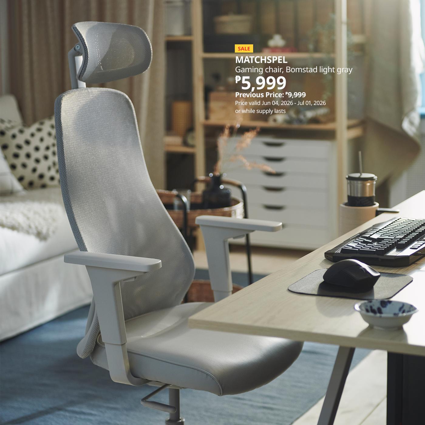 A light grey gaming chair with a headrest is placed in front of a desk with a computer monitor in a modern, well-lit room. A sale price is displayed in the image.