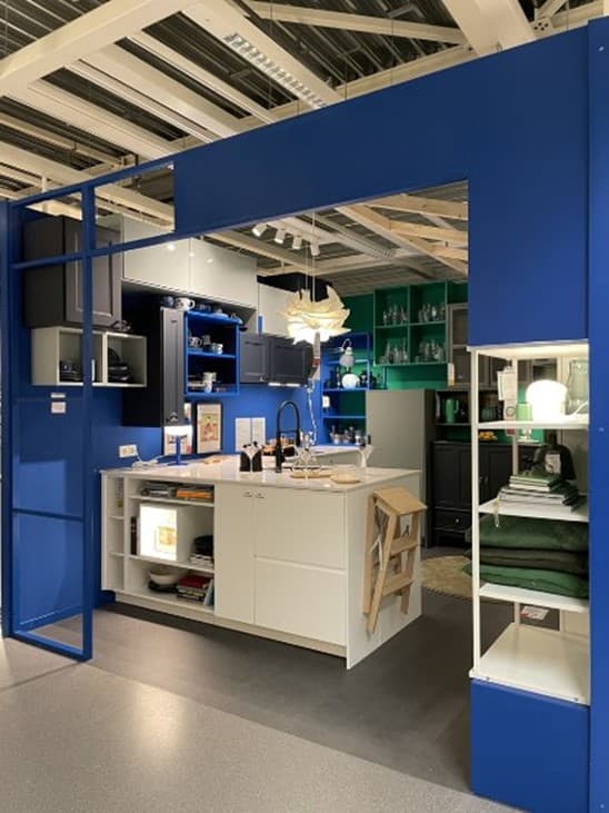 A light, spacious kitchen with a white cooking island and many different cabinets against the wall and many blue elements