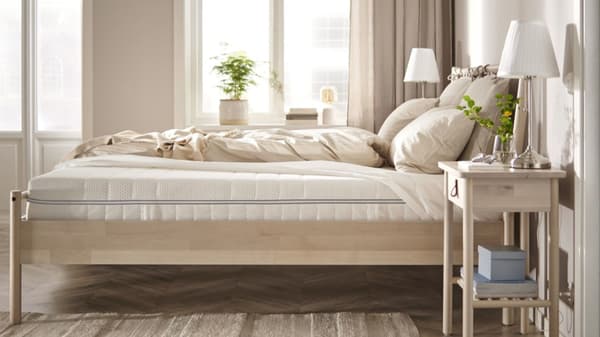 A light wood bed frame with a mattress atop it