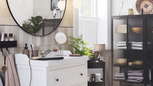 A LINDBYN mirror hangs above a white HEMNES/RÄTTVIKEN wash-stand with two drawers, next to a FRIHULT wall lamp.
