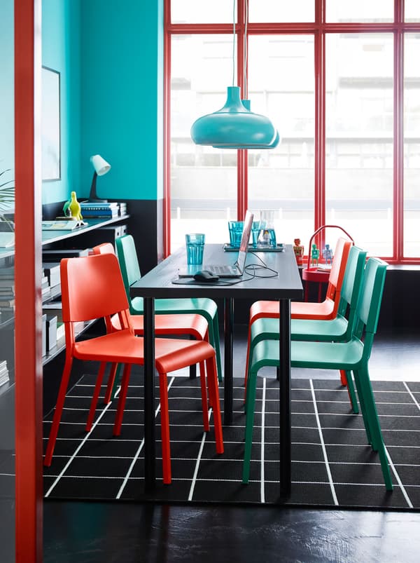 A LINNMON/ADILS table with turquoise and red chairs on a black and white check rug. A turquoise pendant lamp hangs above.