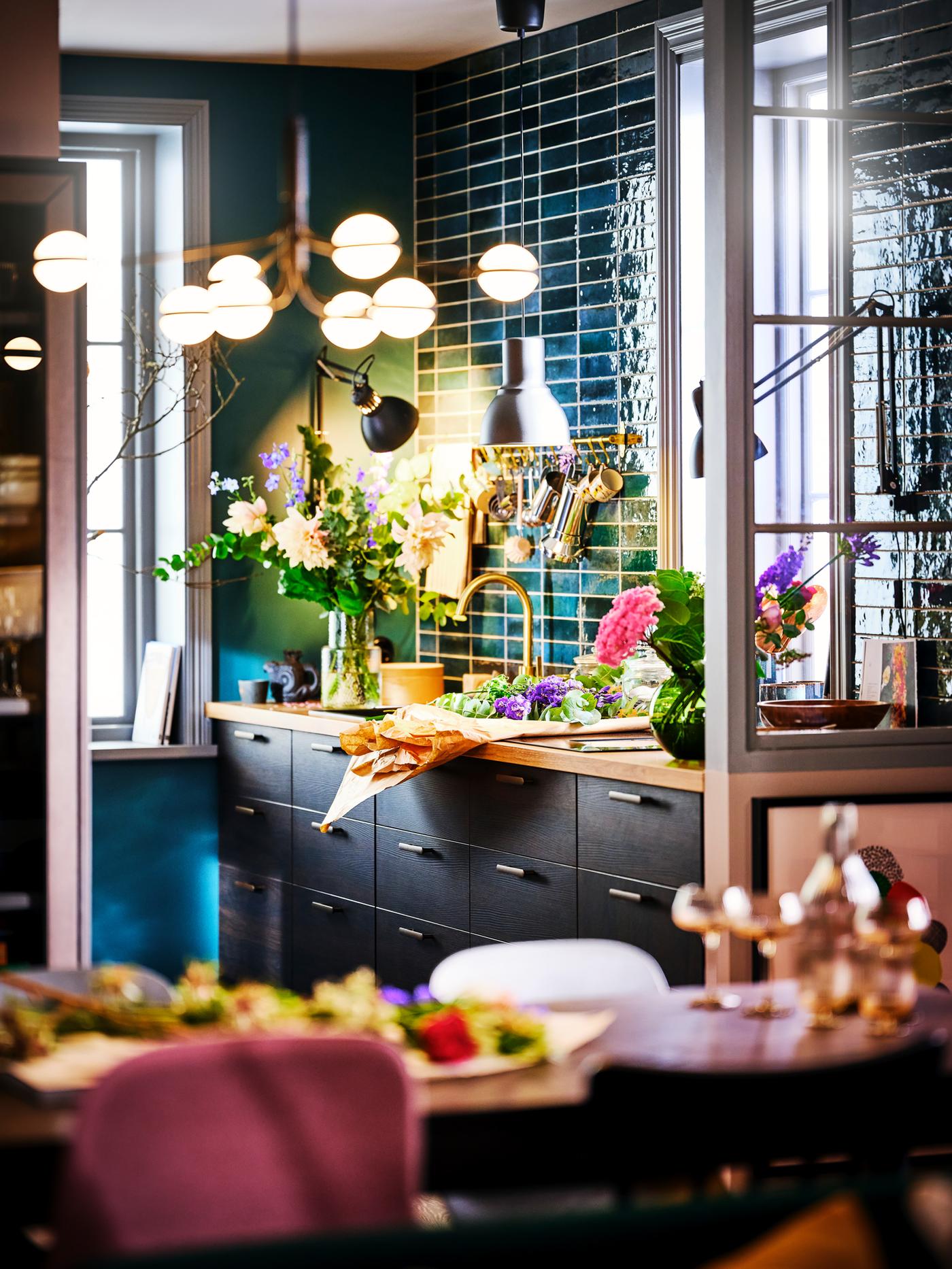 A lit STORSLINGA LED 8-armed chandelier with an ASKERSUND dark brown kitchen in the background.