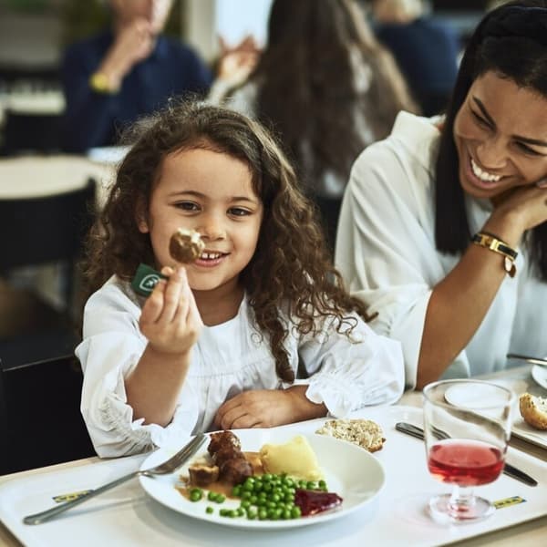 A little girl eating a plate of meatballs in the IKEA restaurant