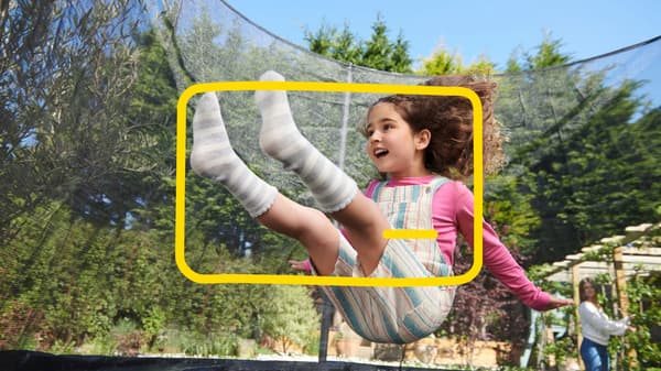 A little girl is bouncing on a trampoline in the garden