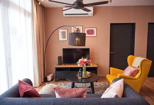 A living room area featuring a sofa, television conslie and a lamp.