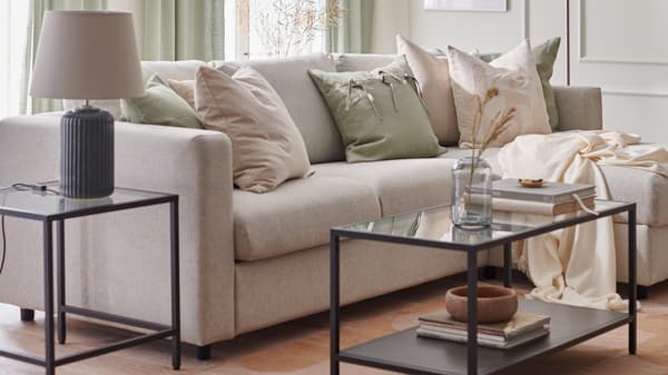 A living room is furnished for spring with a VIMLE sofa, RÖDASK cushion covers and SNÖBYAR lamp on a VITTSJÖ table.