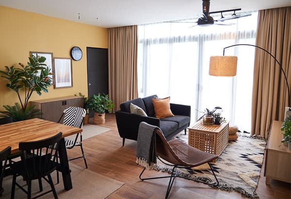A living room setting featuring a sofa, dining table, and chest of drawer. 