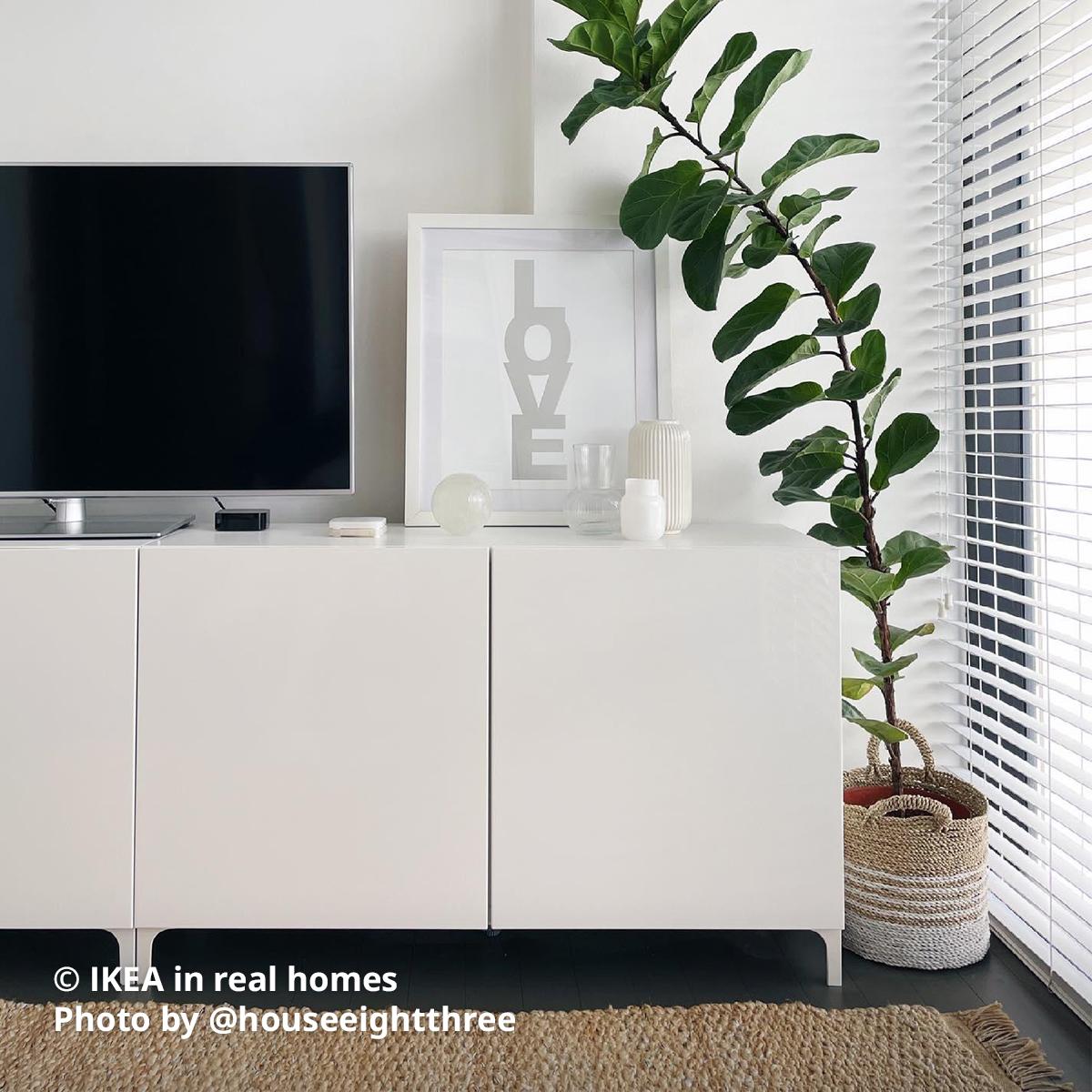 A living room setting with a white BESTÅ storage combination with doors is being used as a TV console with a TV with stand is being placed. Photo by instagrammer @houseeightthree for IKEA in real homes ©