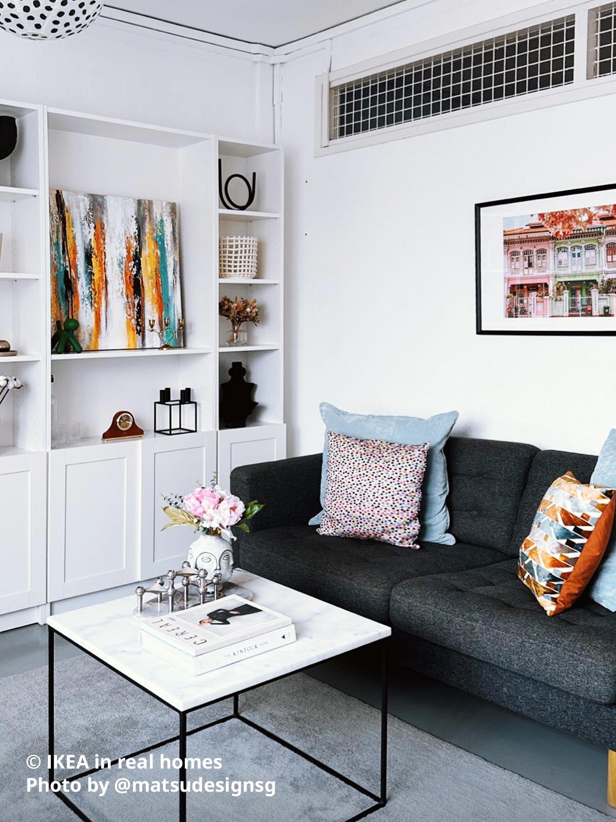A living room setting with white BILLY with OXBERG door placed alongside the wall right next to a gunnared dark grey 3-seat LANDSKRONA sofa with wooden legs. Photo by instagrammer @matsudesignsg for IKEA in real homes ©