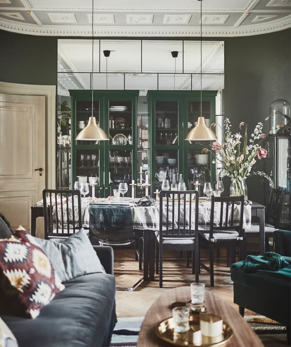 A living room that leads directly to a dining area, with two IKEA LIATORP bookcases with glass doors.