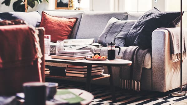 A living room with a beige VIMLE 3-seat sofa, cushions, two throws, and a walnut veneer STOCKHOLM coffee table.