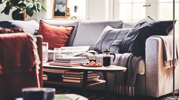 A living room with a beige VIMLE 3-seat sofa, cushions, two throws, and a walnut veneer STOCKHOLM coffee table.