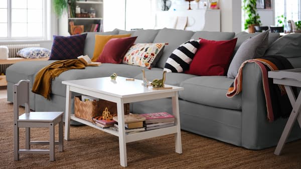 A living room with a grey GRÖNLID 4-seat sofa with chaise longues, and a white LUNNARP coffee table standing next to it.
