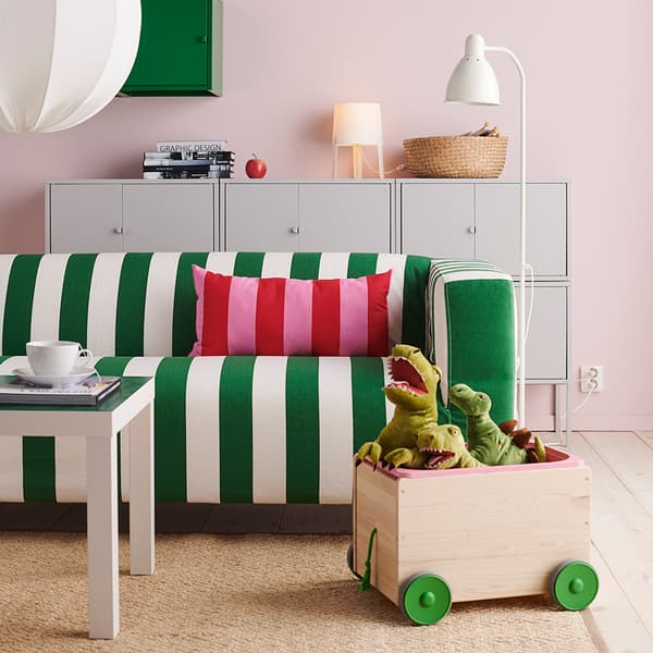 A living room with a KLIPPAN sofa, some LIXHULT grey cabinets, a white LACK table and a trolley full of stuffed dinosaurs.
