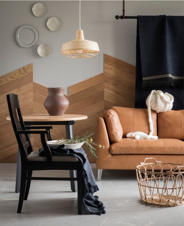 A living room with a sofa, a chair and hanging carpet.