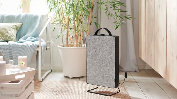 A living room with a white INGMARSÖ sofa, a jute rug, a FÖRNUFTIG air purifier and a tray with scented block candles.