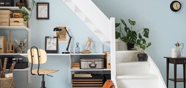 A living room with a workspace created in the space under the stairs.