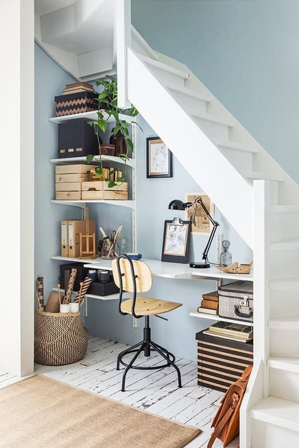 A living room with a workspace created in the space under the stairs.