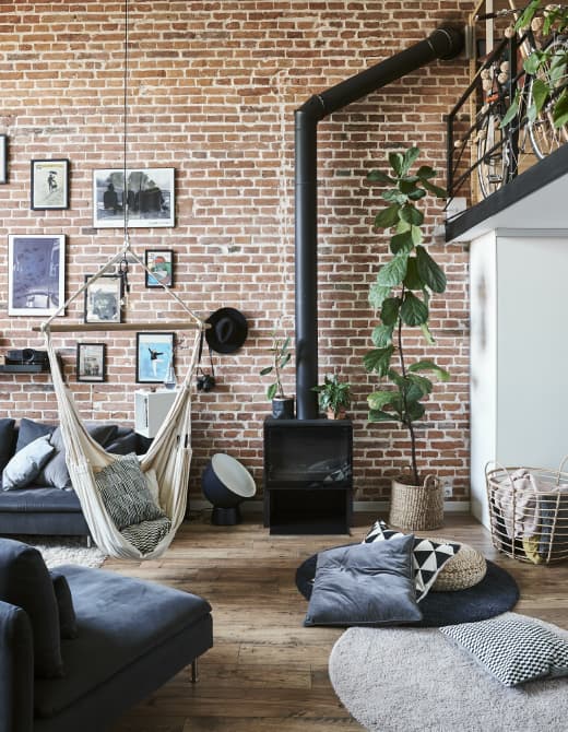 A living room with exposed brick wall and a hammock.