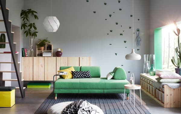 A living room with green sofa, side table and storage cabinets.