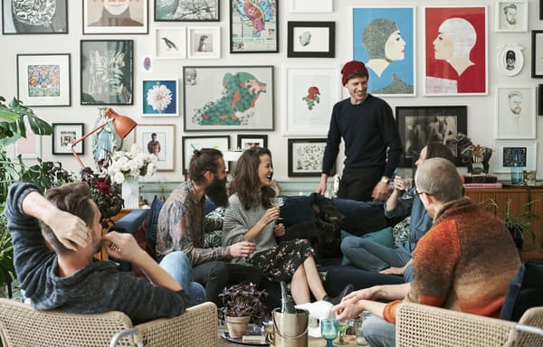 A living room with six people gathered around a sofa.