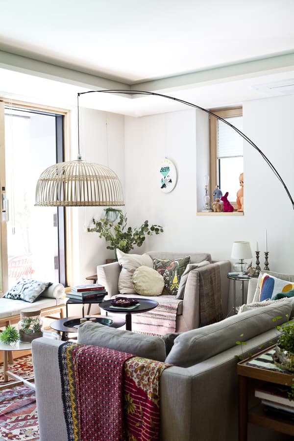 A living room with sofa, armchair and large floor lamp.
