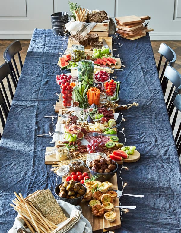 A long blue table, surrounded by blue chairs with a full spread of already-prepared foods for lunch.