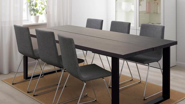 A long brown dining table with gray chairs around it.