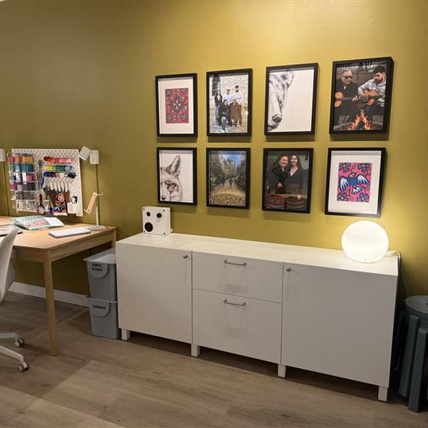 A long shot of a room setting in a store focusing on a wall cabinet and pictures hanging in frames above.
