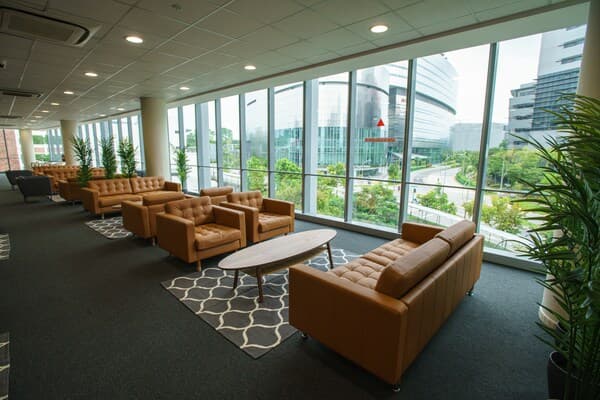 A lounge area featuring mustard yellow sofas placed facing each other on top of a grey and white rug and an oval table.
