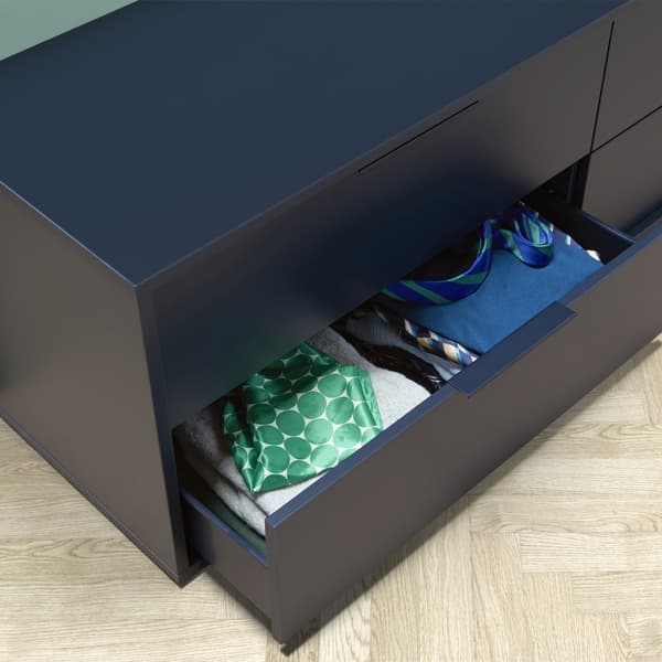 A low chest of drawers with a drawer open to reveal folded clothes.