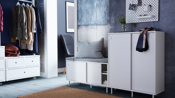 A MACKAPÄR bench with storage with a gray cushion on it by a MACKAPÄR cabinet with a vase and scarf on top in a hallway.
