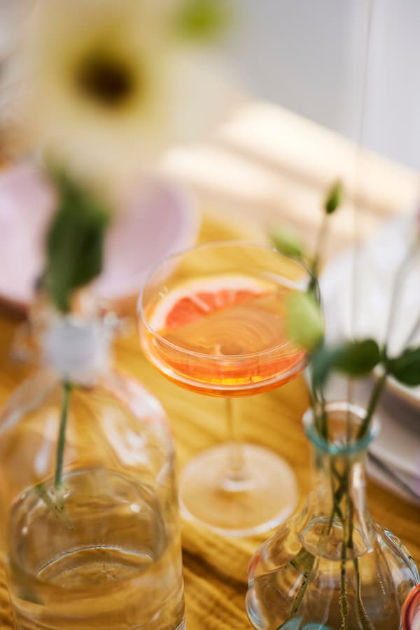 A magherita glass with a cocktail decorated with half a grapefruit slice.