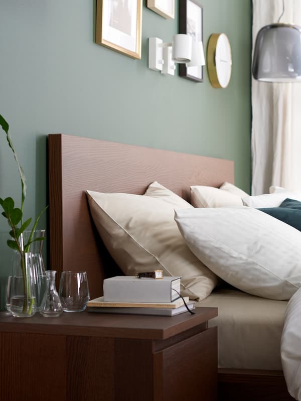 A MALM bed frame and bedside table in black brown veneer and a quilt cover, pillowcases and curtains in white.