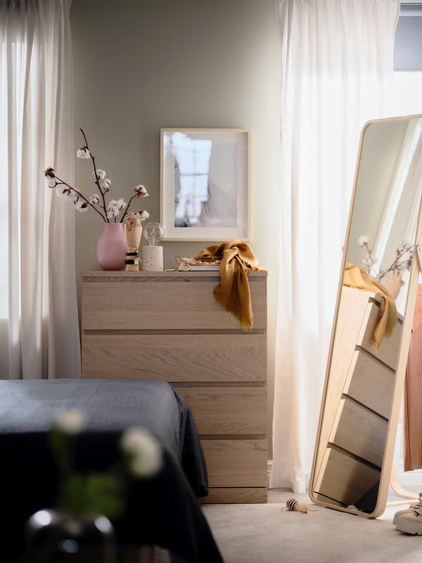 A MALM drawer unit in the bedroom next to a mirror.