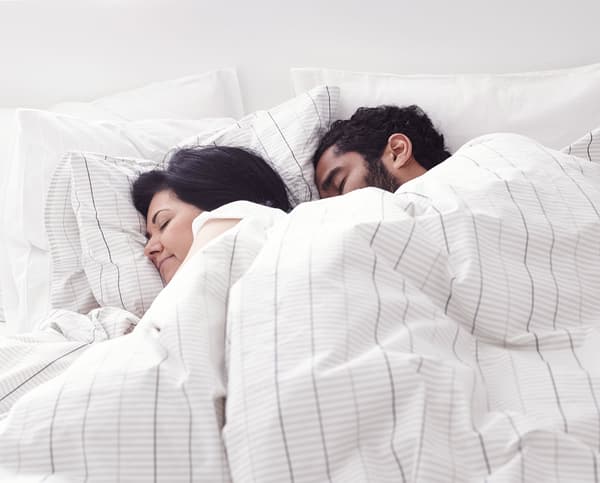 A man and woman sleeping in bed together.