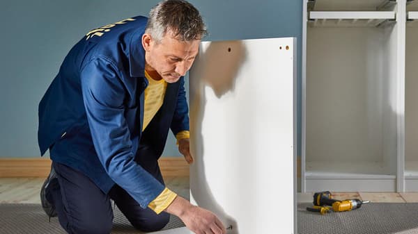 A man assembling a wardrobe.