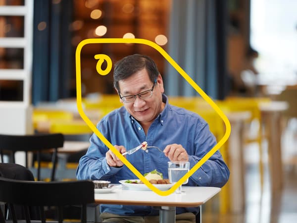 A man eating meatballs in an IKEA restaurant.