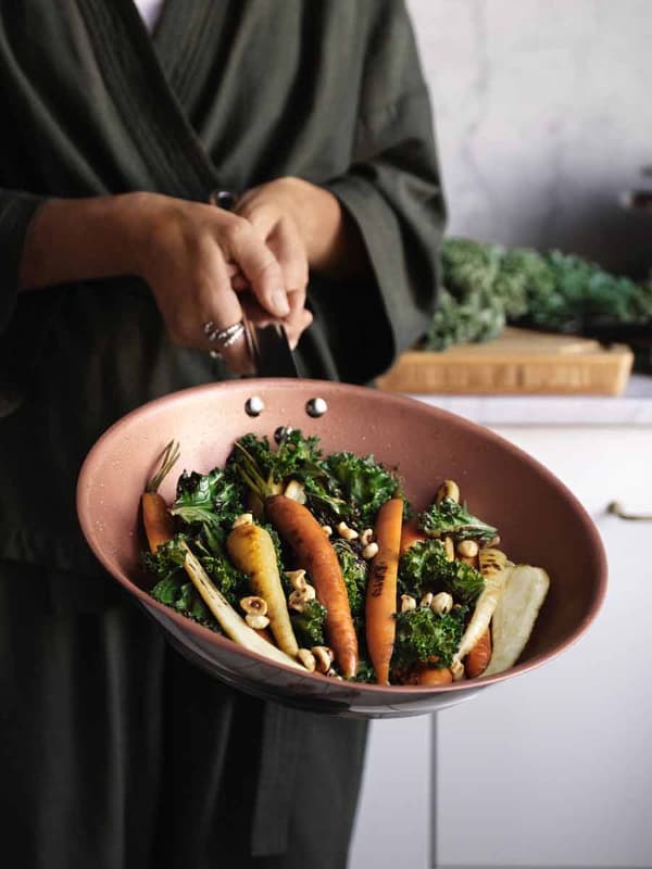 A man holds a Pan in his hands with vegetables.