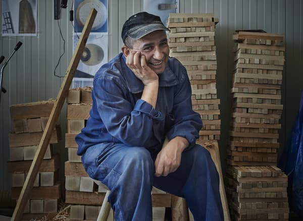 A man in a blue boiler suit inside a workshop.