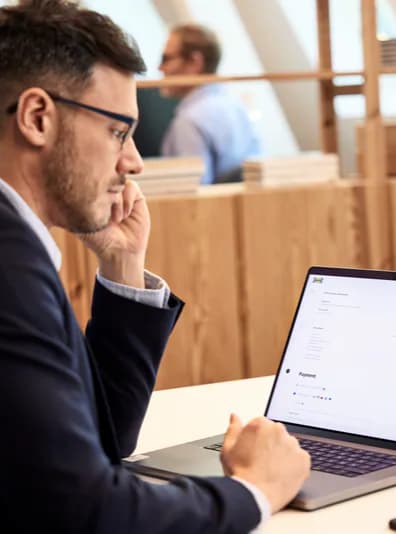 A man in a suit browsing IKEA online on his laptop.