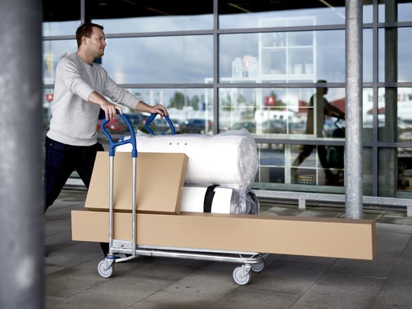 A man is pushing ahead with the product he bought in an L-cart.